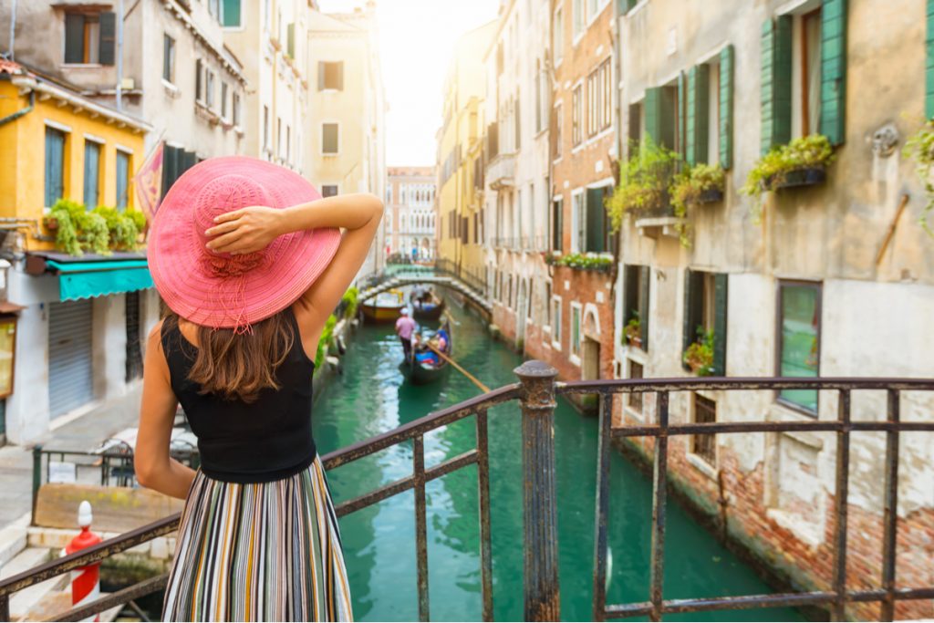 Woman in pink hat overlooking Venice canal.