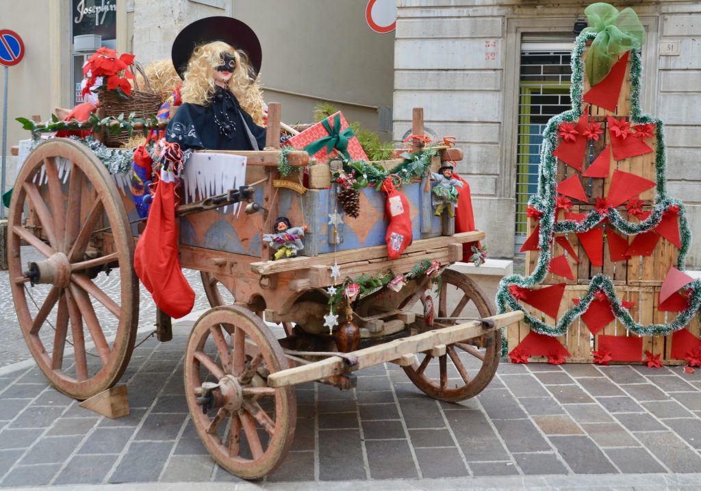 Old wagon filled with gifts and witch. hay bales decorated with ribbons and piled as christmas tee