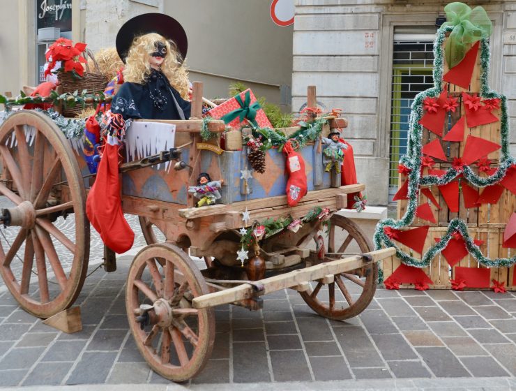 Old wagon filled with gifts and witch. hay bales decorated with ribbons and piled as christmas tee