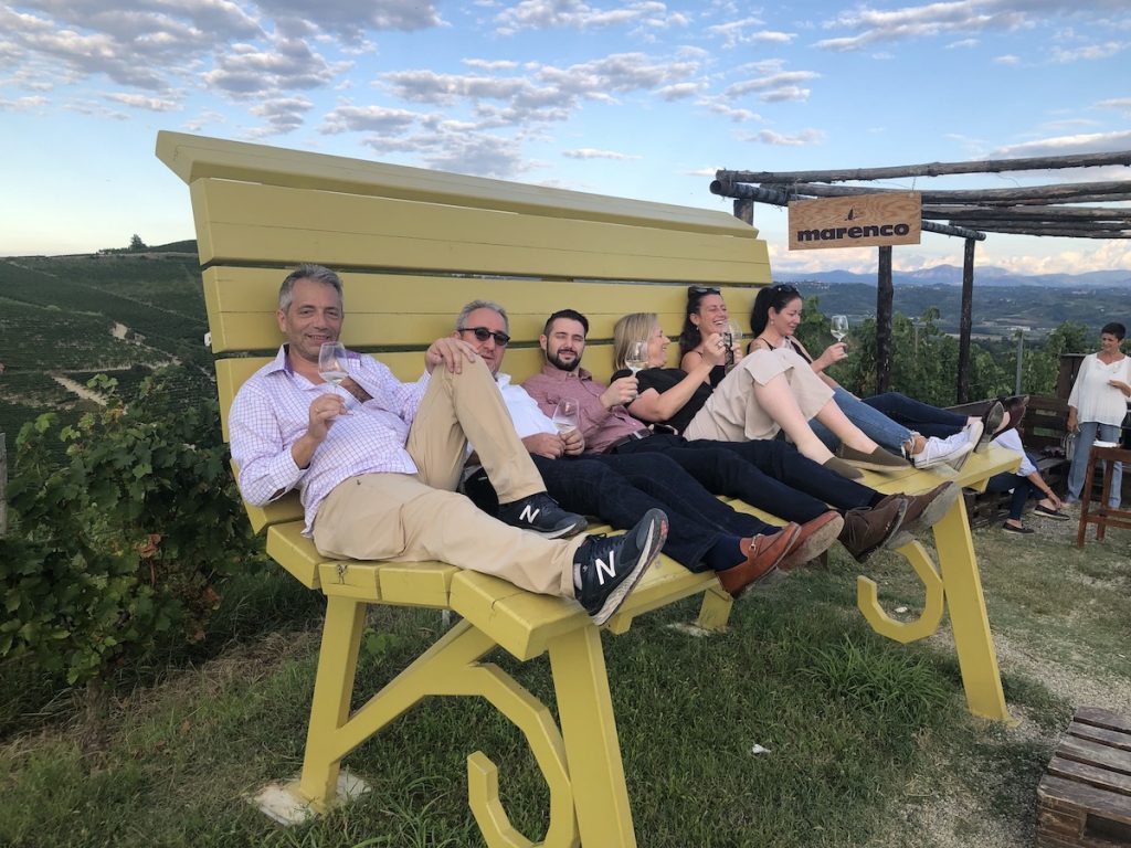 Friends sitting on large bench in Piedmont vineyard.