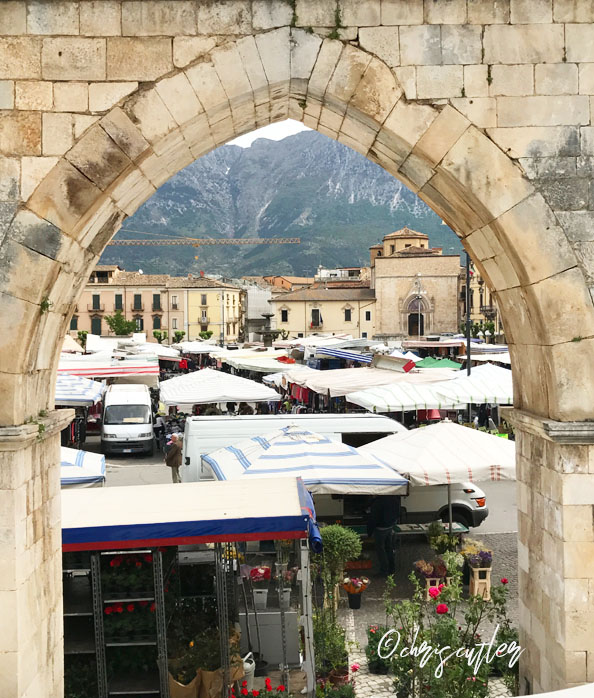 Italian market tents through the archway of the Sulmona aqueduct