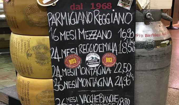 piles of cheese wheels with sign announcing cost