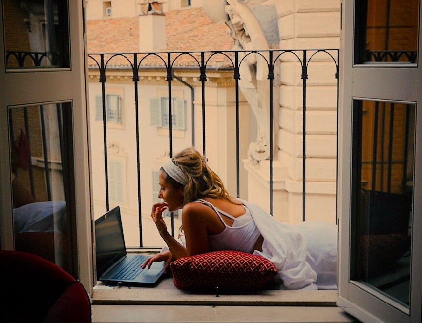 Kylie Flavell on laptop on balcony in Rome.