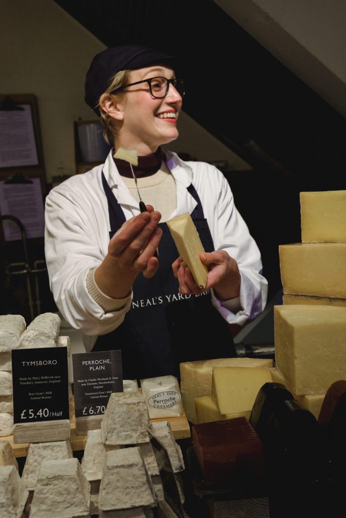 Katie Quinn working as cheesmonger holding cheese