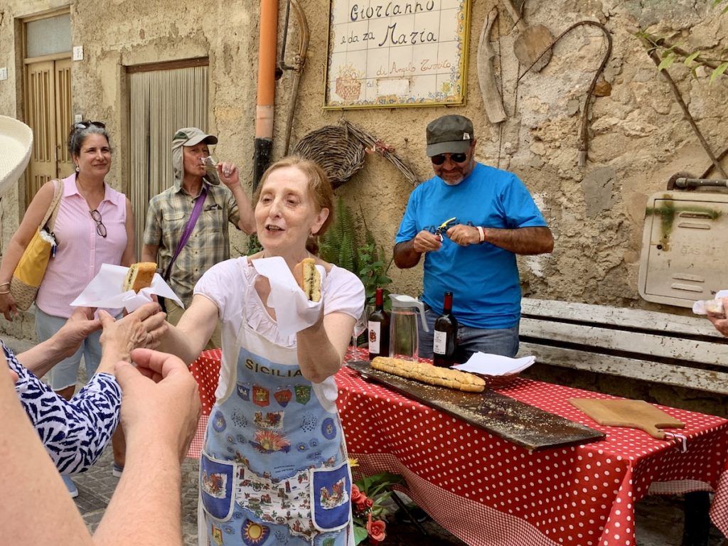 Rural Tourism and Experiential Travel in Sicily: woman handing out food to tourist