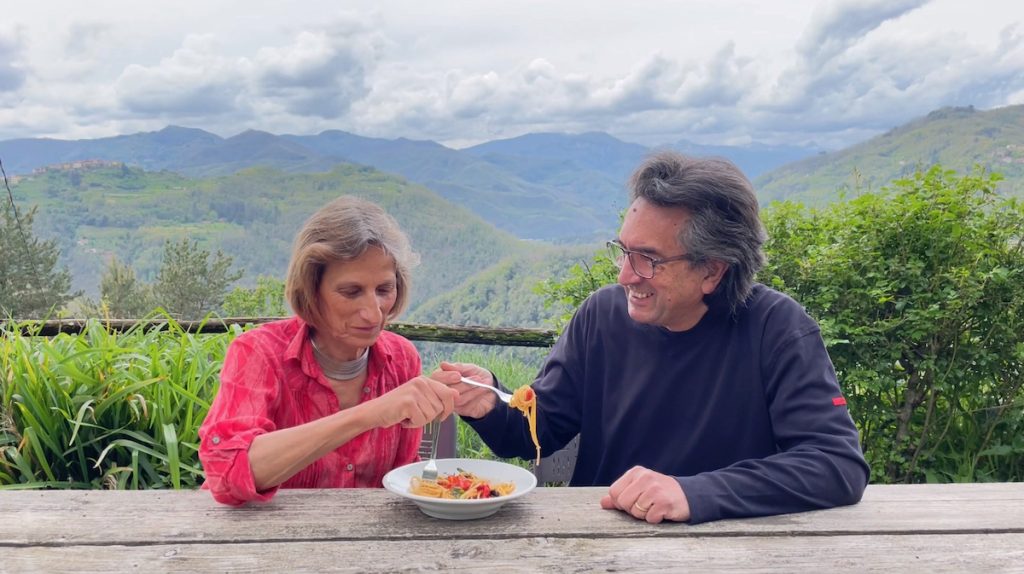 Tuscan Countryside : couple eat pasta with a backdrop of mountain ranges in Italy