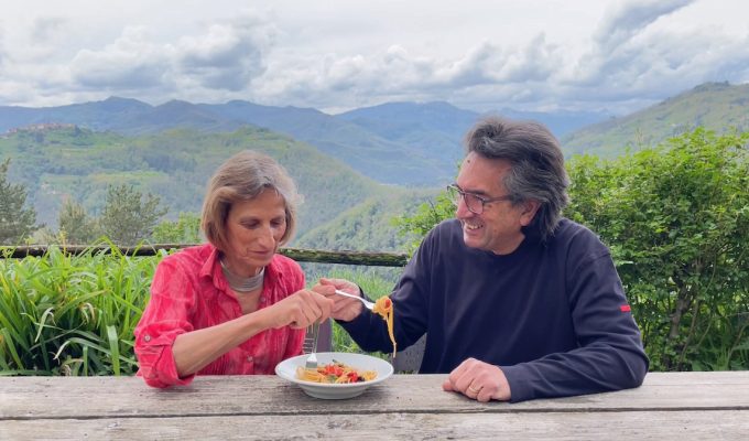 Tuscan Countryside : couple eat pasta with a backdrop of mountain ranges in Italy