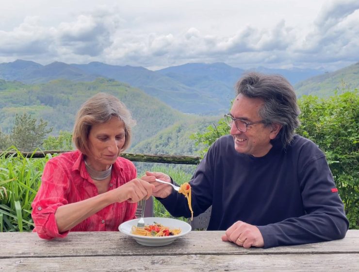 Tuscan Countryside : couple eat pasta with a backdrop of mountain ranges in Italy