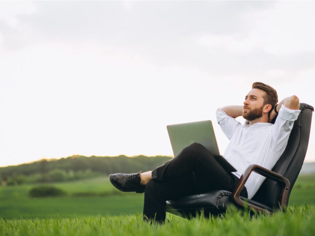 Digital Nomad Visa for Italy - man sitting with laptop in field