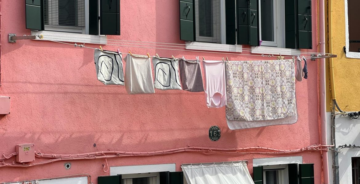 Burano Italy - coloroful town with pink building and laundry hanging from window