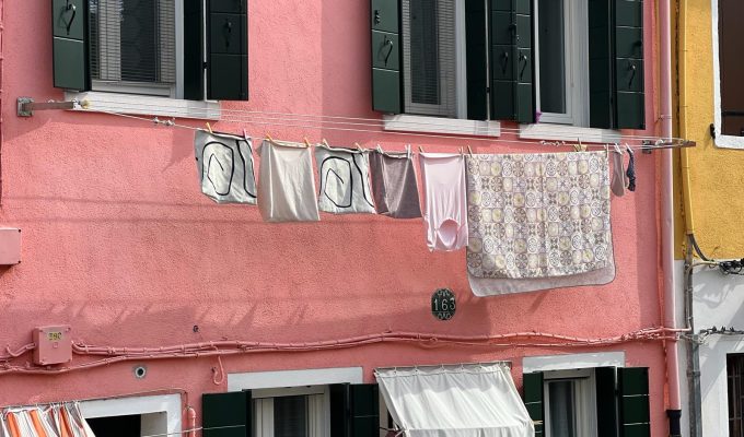 Burano Italy - coloroful town with pink building and laundry hanging from window