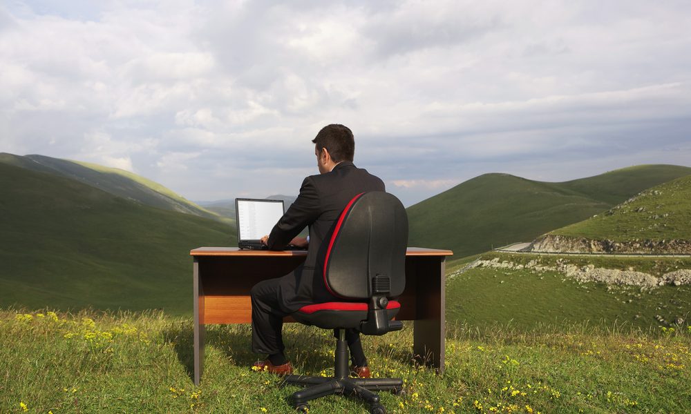 man working on laptop in a mountainous setting