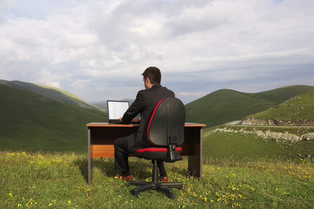 man working on laptop in a mountainous setting