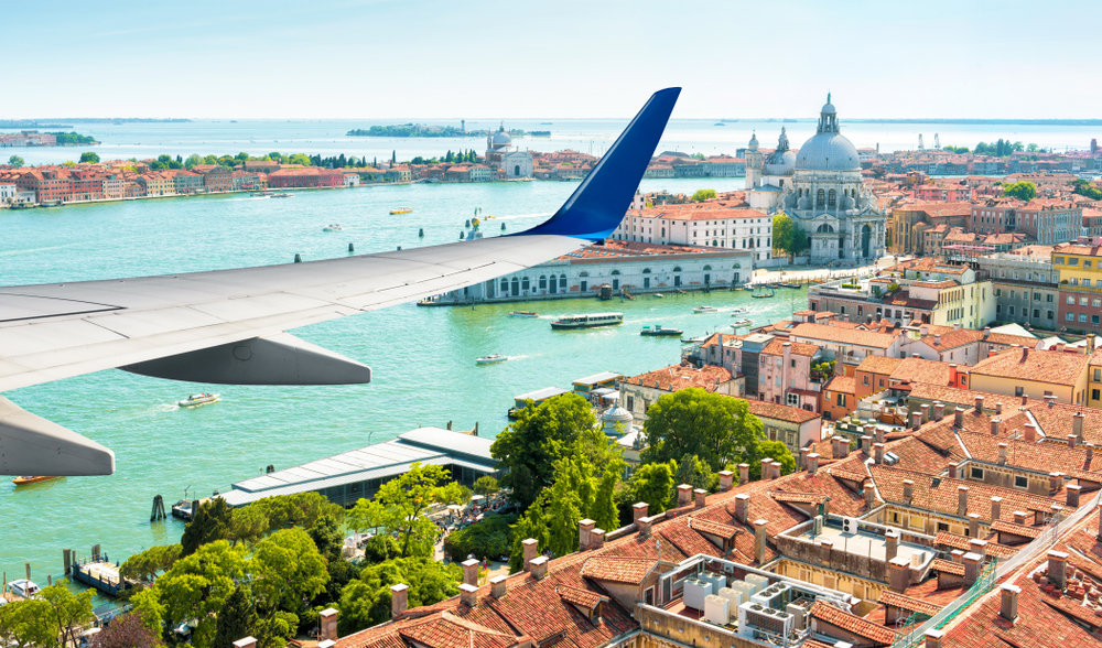 booking flights to Italy: airplane flying over Venice