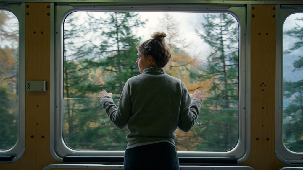 Solo travel in Italy. Woman on train looking out of window at autumn landscape in Italy.