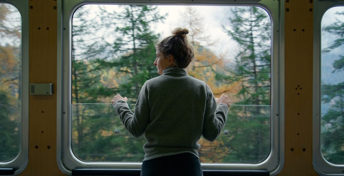 Solo travel in Italy. Woman on train looking out of window at autumn landscape in Italy.