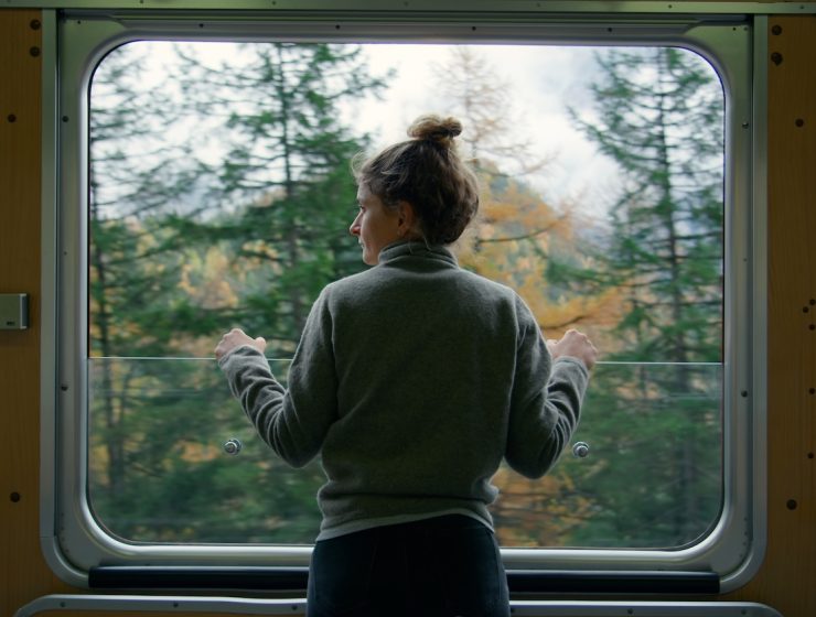 Solo travel in Italy. Woman on train looking out of window at autumn landscape in Italy.