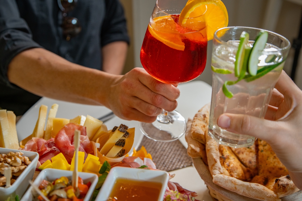 couple cheering with cocktails with apperitivi on table