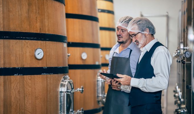 Italian wine market 2024 -- Winemakers evaluating wine from large barrels