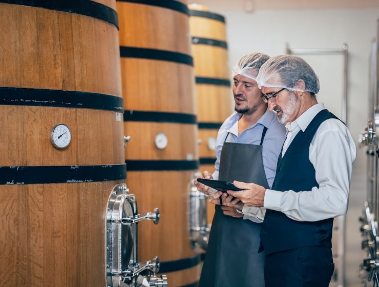 Italian wine market 2024 -- Winemakers evaluating wine from large barrels