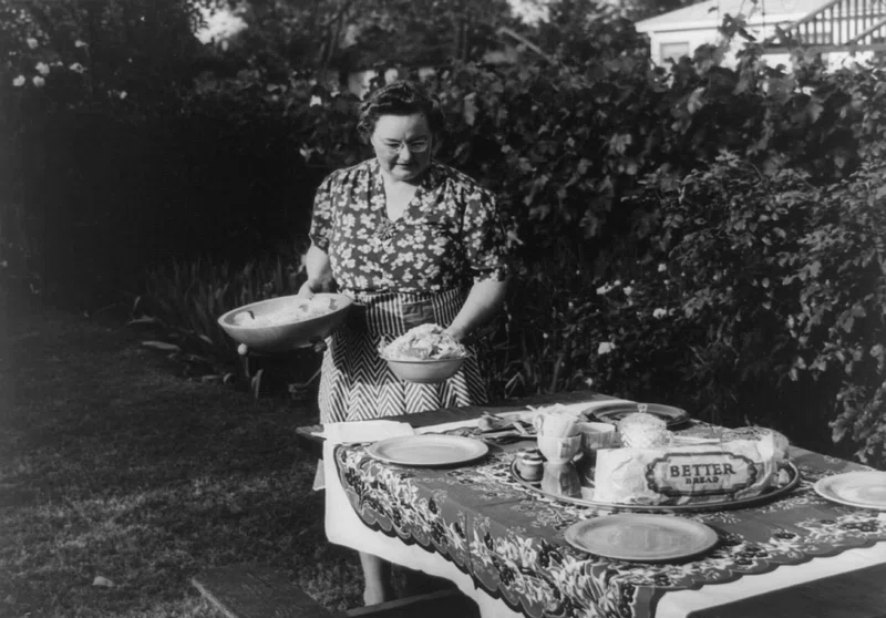 gender roles in Italy - black and white photo of woman setting the table outside