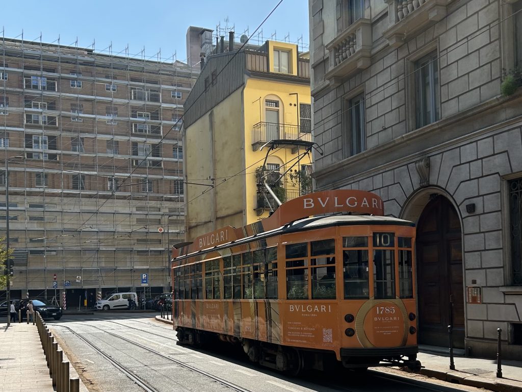 Iconic yellow tram on a lively street in Milan.