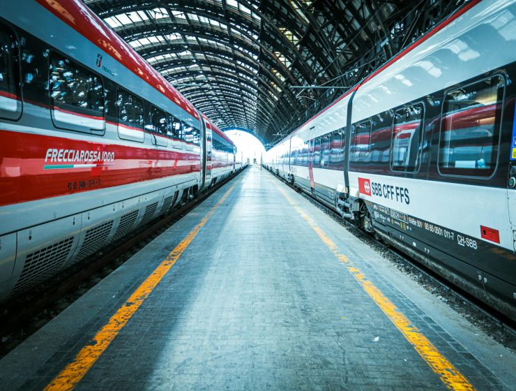 A busy train station with multiple trains on the tracks, representing the convenience of taking day trips from Milan.