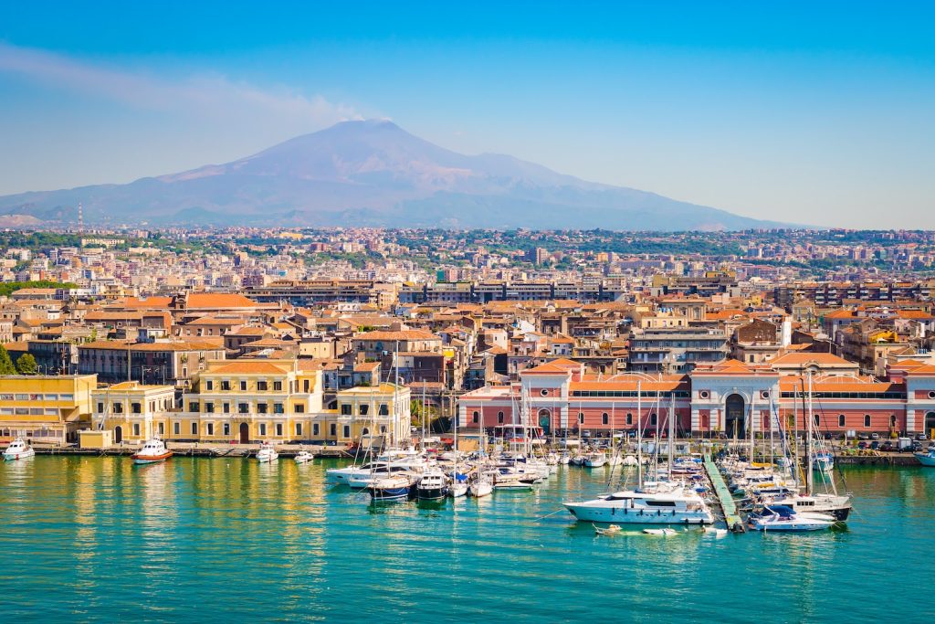 Mount Etna is the backdrop to a waterfront town in Sicily