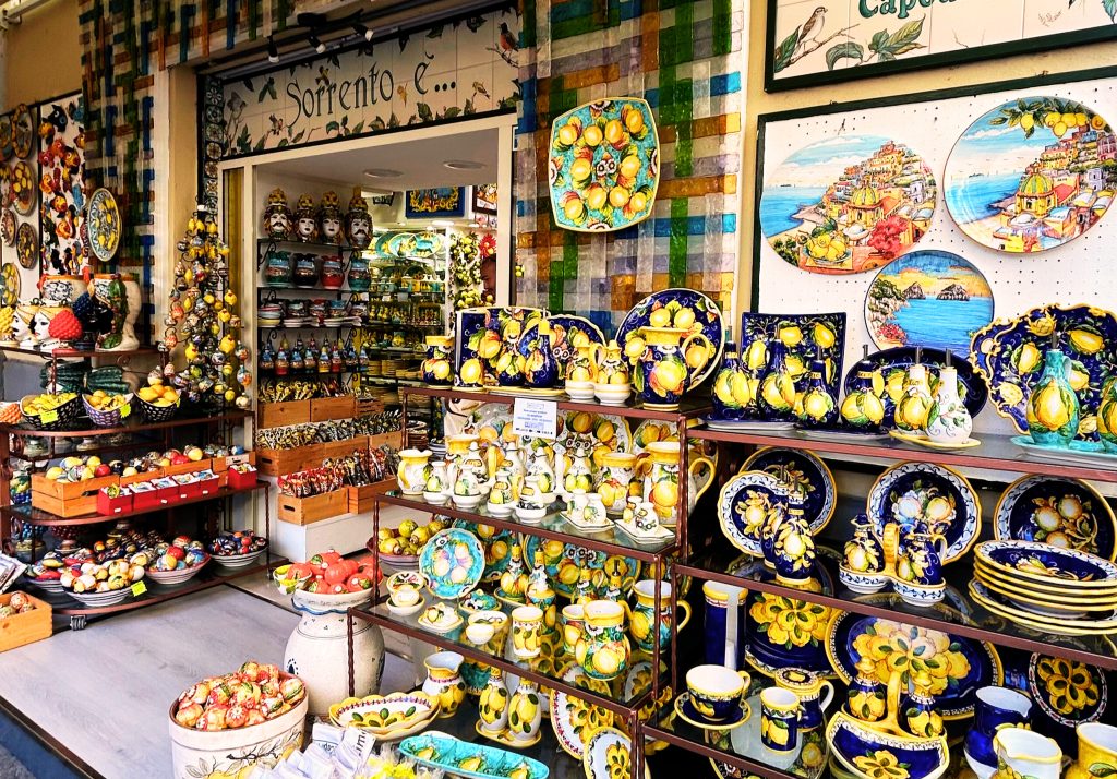A vibrant storefront of the shop Sorrento È, filled with handcrafted maiolica pottery and ceramic plates featuring iconic lemon designs, for an article on where to shop in Sorrento.