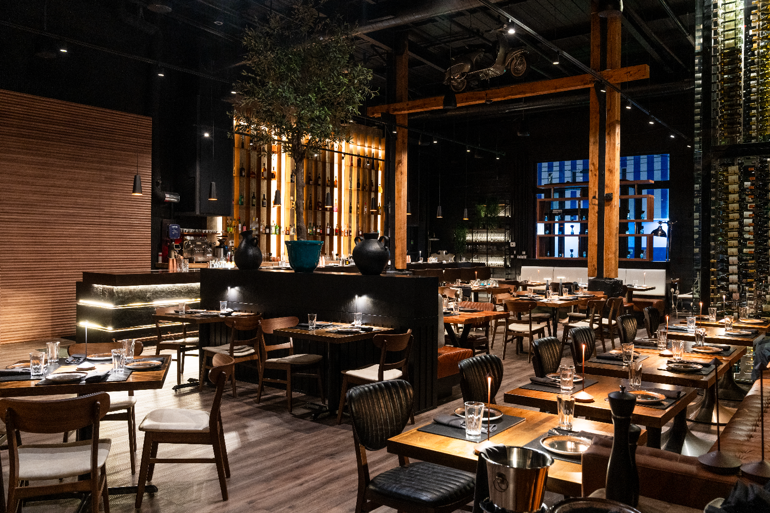 Interior of Francesco Martucci Miami featuring a moody dining room with dark wood elements, black finishes, and warm ambient lighting.