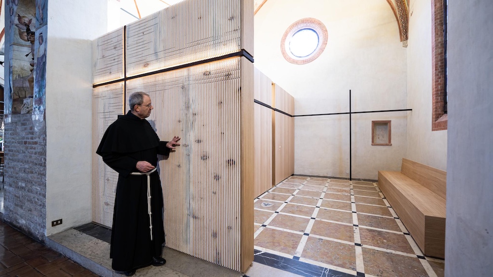 Monk examining sculptural wood design by 583 Studio