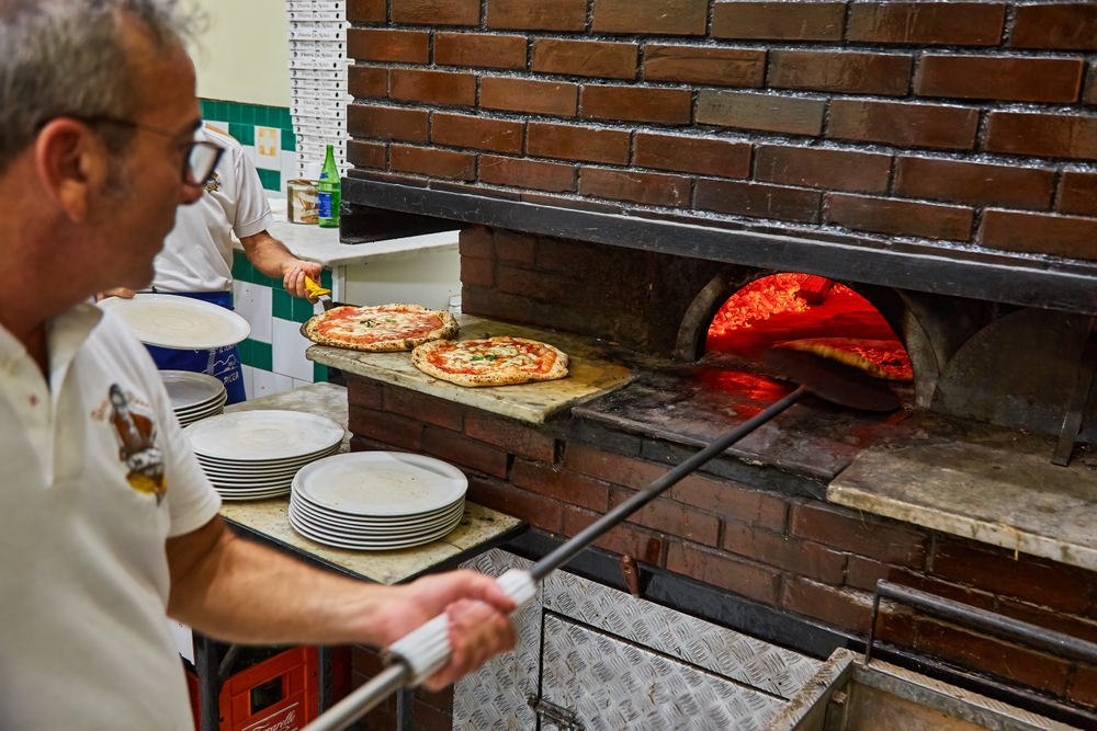 L'Antica Pizzeria da Michele. Naples pizzeria. Naples, Italy. Man making Neopolitan pizza in a wood oven.