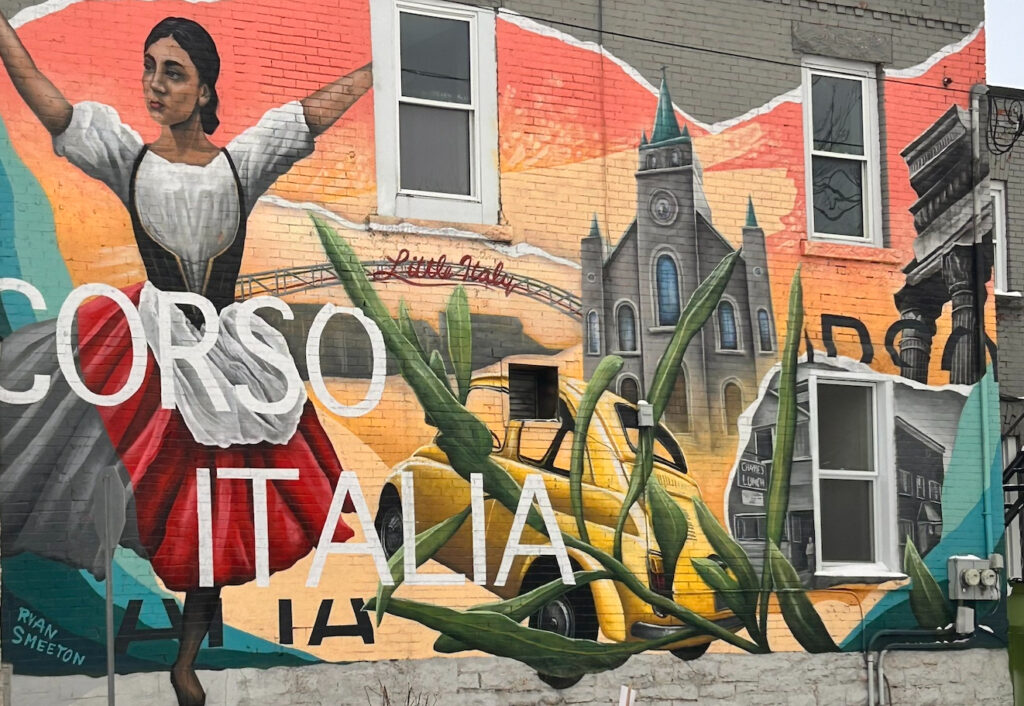 A colorful outdoor brick wall mural on Preston Street in Ottawa's Little Italy, featuring a woman in traditional Italian dress, a classic yellow Fiat 500, a church building, and the bold text "Corso Italia" painted by Ryan Smeeton.