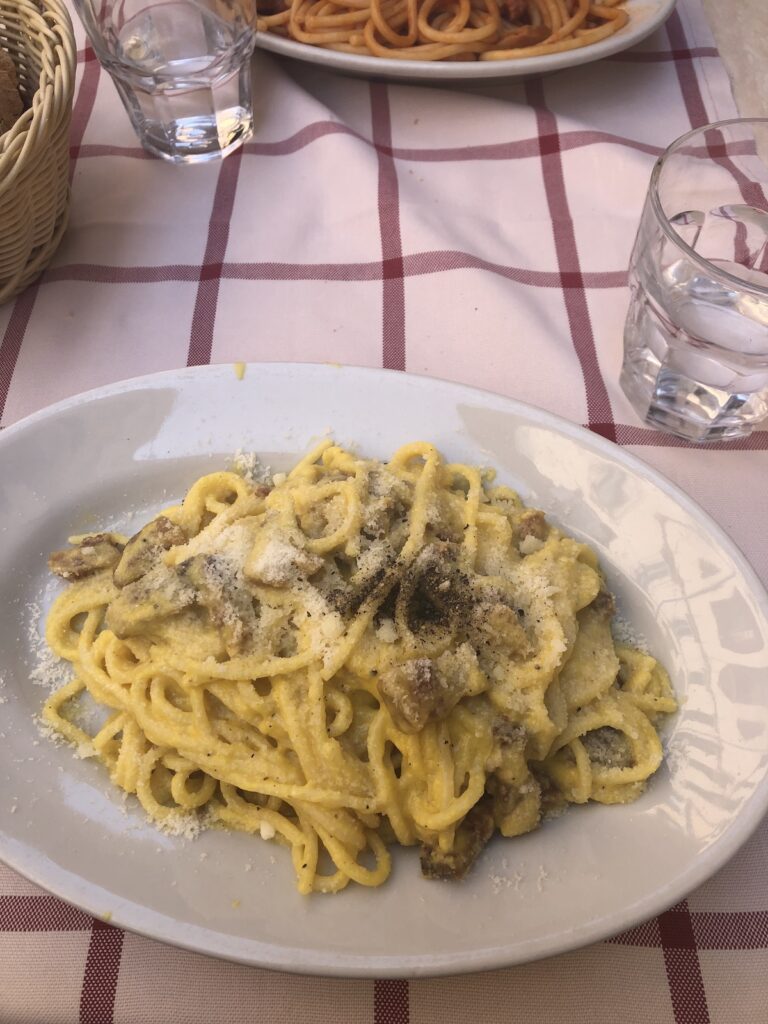 Authentic Roman carbonara served outdoors in Rome with pasta, guanciale, egg, and Pecorino Romano.