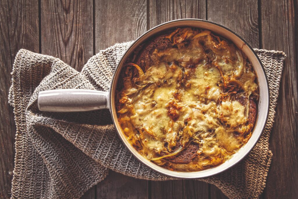 A bowl of seupa vapellenentse, a traditional baked soup from Valle d'Aosta featuring layered rye bread, cabbage, broth, and melted fontina cheese.