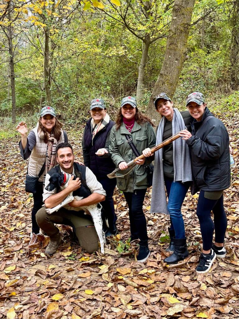 A group participating in a traditional truffle hunting excursion in the Tuscan woods with a dog and guide.
