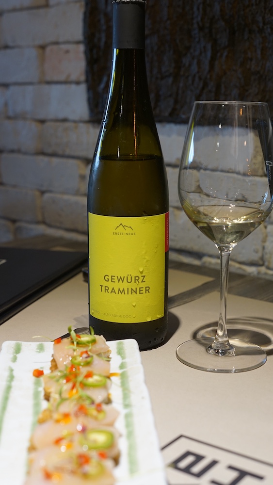 Bottle of Erste+Neue Gewürztraminer from Alto Adige alongside Crispy Rice Hamachi with yuzu truffle at Ke-uH Japanese fusion restaurant in Weston, Florida.