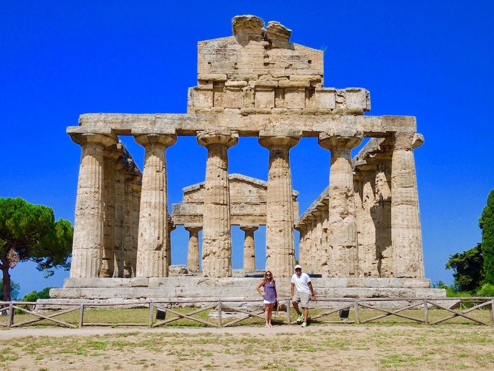Sandy and Phil standing in front of the ancient Greek Temple of Neptune at Paestum, a UNESCO World Heritage Site in Campania, Italy.