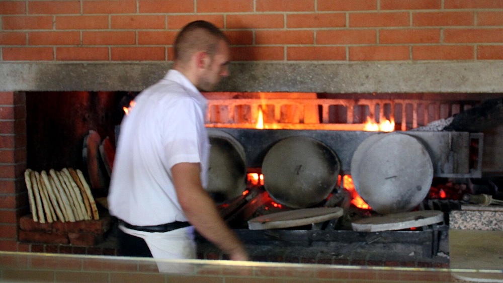 Traditional Umbrian torta al testo flatbread being prepared on a hot cooking surface.