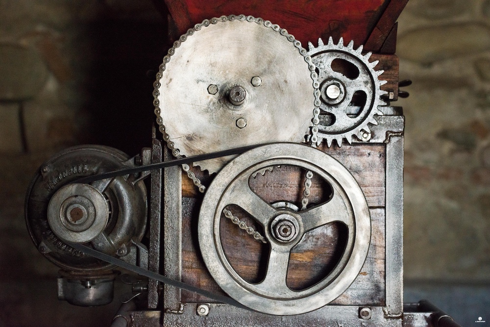 Historic grape-processing machinery with metal gears and pulleys displayed at Librandi's agricultural museum in Calabria.